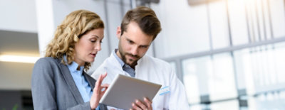 Osoba drži tablet i razgovara sa drugom osobom