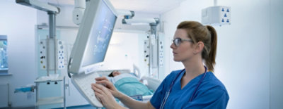 Žena u plavoj uniformi i naočarima koristi računar.