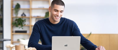 A person sitting at a table looking at a laptop.