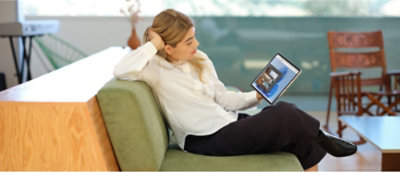 Een persoon die een wit shirt en een zwarte broek draagt en op een groene bank zit