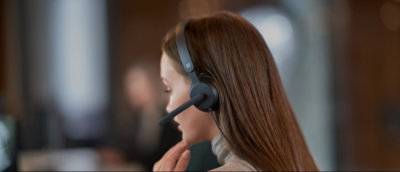 Personne aux cheveux longs portant des écouteurs dans un bureau.