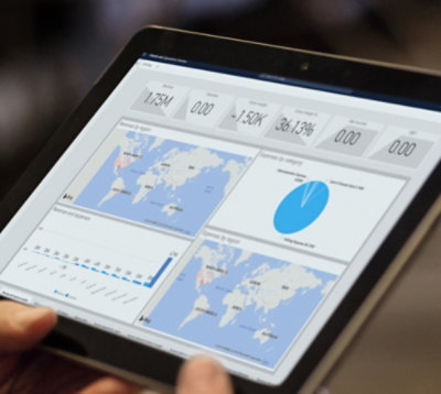 Osoba drži tablet koji prikazuje grafikone analitike, uključujući mape i grafikone, koji se odnose na metriku globalnih podataka.