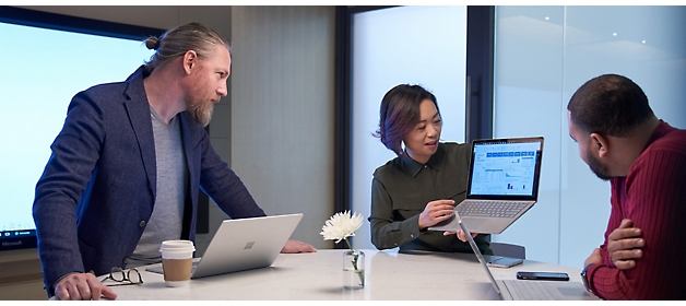 Trei profesioniști discută pe un laptop într-un mediu modern de birou.