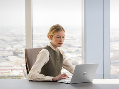 Ženska sedi pri mizi in uporablja prenosnik.