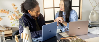 Dve osebi sedita za mizo s prenosnikoma in se pogovarjata