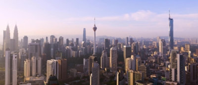 Aerial view of a cityscape featuring numerous buildings and skyscrapers under a cloudy sky.