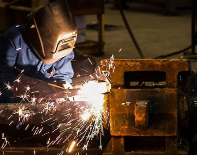 A person wearing a welding mask while welding a metal piece.
