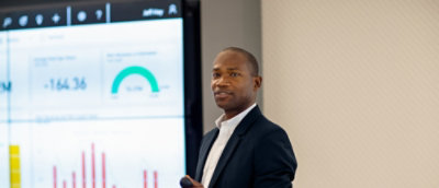 Ein Mann in einem Anzug, der vor einem Computerbildschirm steht.