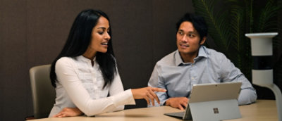 Ein Mann und eine Frau, die an einem Tisch mit einem Laptop sitzen.