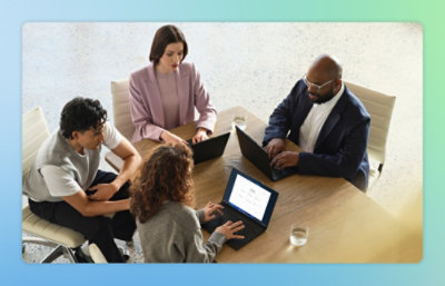 Eine Gruppe von Menschen, die mit Laptops um einen Tisch sitzen