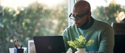 Ein Mann, der eine Brille trägt und auf einen Laptop blickt
