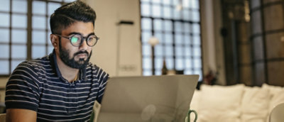 Ein Mann mit Brille und Bart, der auf einen Laptop schaut