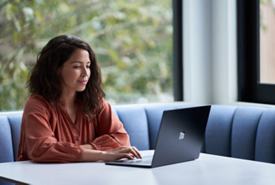 テーブルの前に座ってノート PC を使用している女性。