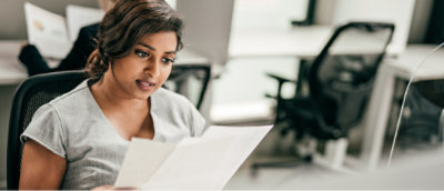 A woman sitting in a chair reading a paper.