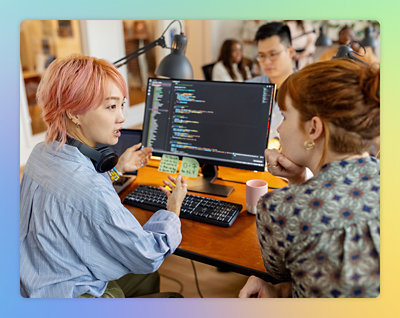 A group of people sitting at a desk looking at a computer screen.