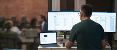 A man sitting at a desk with a laptop and a computer.