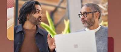 Мужчина в очках и сером свитере разговаривает с другим мужчиной.