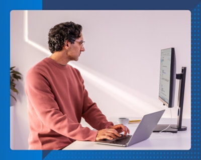 Мужчина в красном свитере печатает на ноутбуке за столом.