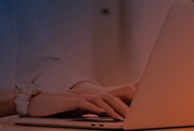 A close-up of hands typing on a laptop keyboard.