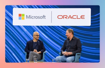Two men sitting and talking on stage in front of a backdrop displaying the Microsoft and Oracle logos