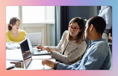 A group of people sitting at a table with laptops.