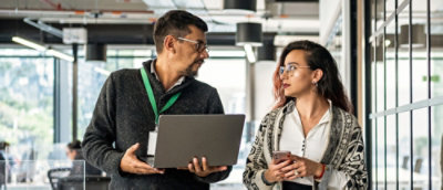 A man and woman holding a laptop and cellphone.