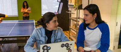 Two women in a discussion, one appears pensive while listening to the other.