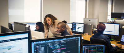 Skupina lidí pracujících na počítačích.