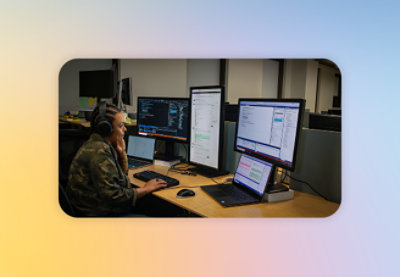 Žena, která sedí u stolu a před sebou má dva monitory