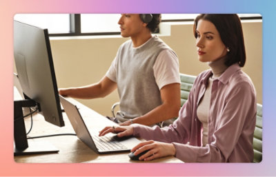 2 人の専門家が笑顔でノート PC で作業しています。