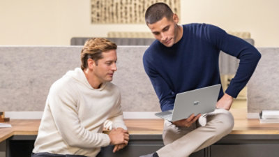 Two persons sitting at a table with a laptop.