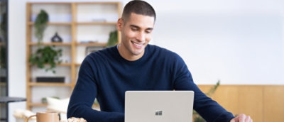 ノート PC が置かれたテーブルに向かって座っている人。