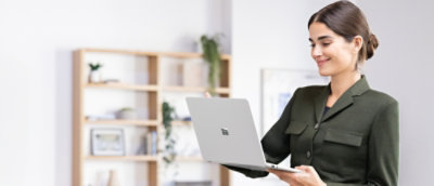 机に向かって座り、ノート PC を持っている人。