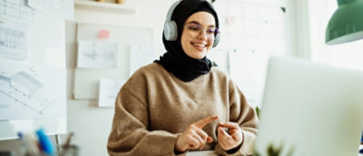 何かを指さしているヘッドホンを着用して茶色のセーターを着ている人。