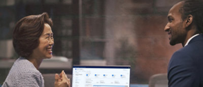 話し合っている青いシャツを着た男性と、グレーのシャツを着た女性。