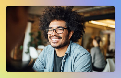 A man with curly hair and glasses smiling.