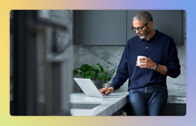 A man holding a cup and using a laptop.