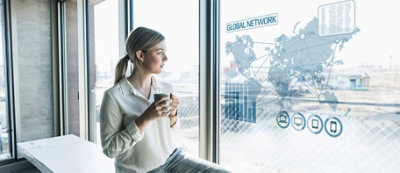 A person sitting in front of a window holding a cup