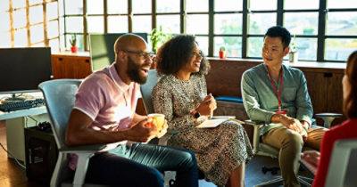 Tri osobe sede u kancelariji i opušteno razgovaraju. Jedna od njih pije iz šolje, a jedna drži beležnicu