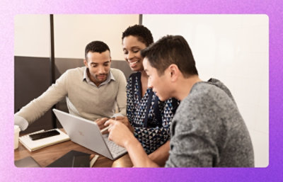 Colleagues collaborating around a laptop in a meeting room.
