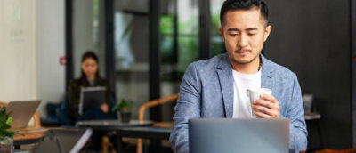 Professional working on laptop with coffee in workspace