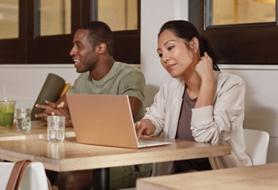 两个人坐在咖啡厅里,其中一个正在使用笔记本电脑.