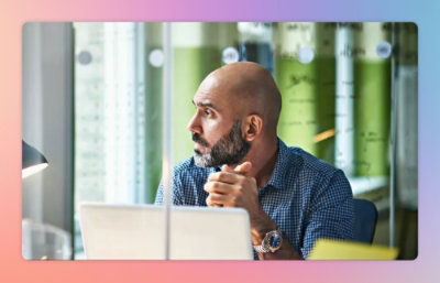 A man with a beard looking out a window.