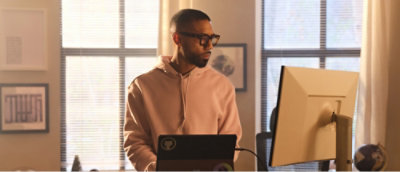 A man wearing glasses looking at the laptop screen and smiling