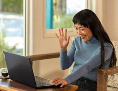 women saying hi by looking at laptop.