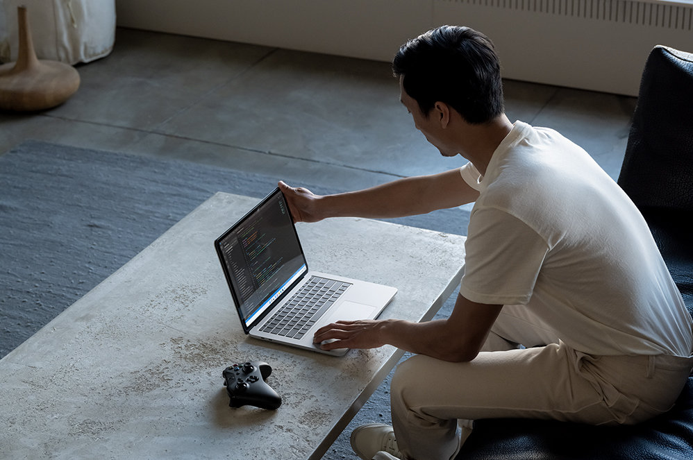 A person uses Surface Laptop Studio in laptop mode to code in a living room.