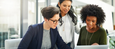 three women discussing looking at the laptop.