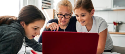 Group of three generation women lookin at laptop