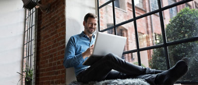 A person sitting on a fur rug using a computer