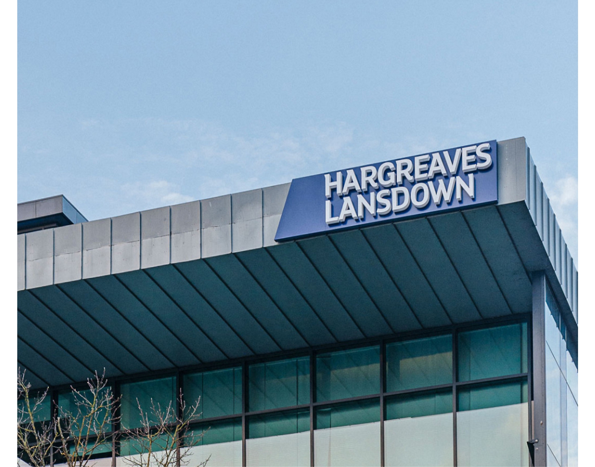 Надпис „hargreaves lansdown“ на върха на модерна сграда с ясно небе на заден план.